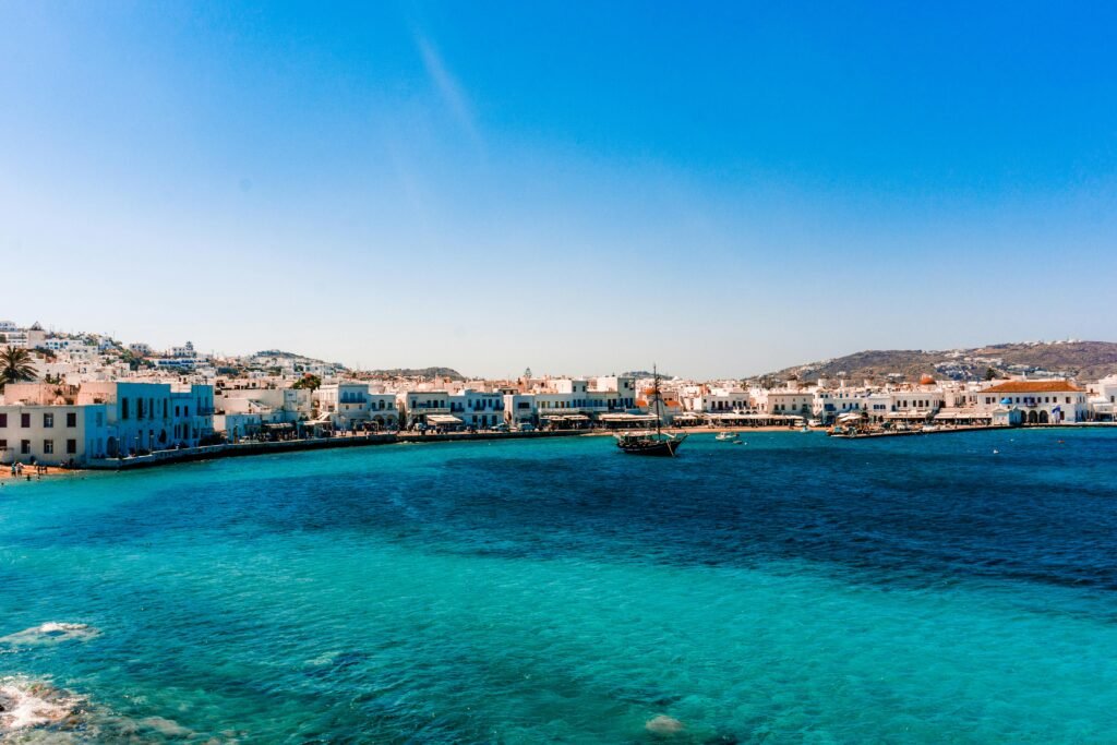 A breathtaking view of Mykonos Harbor with vibrant blue waters under a clear summer sky.